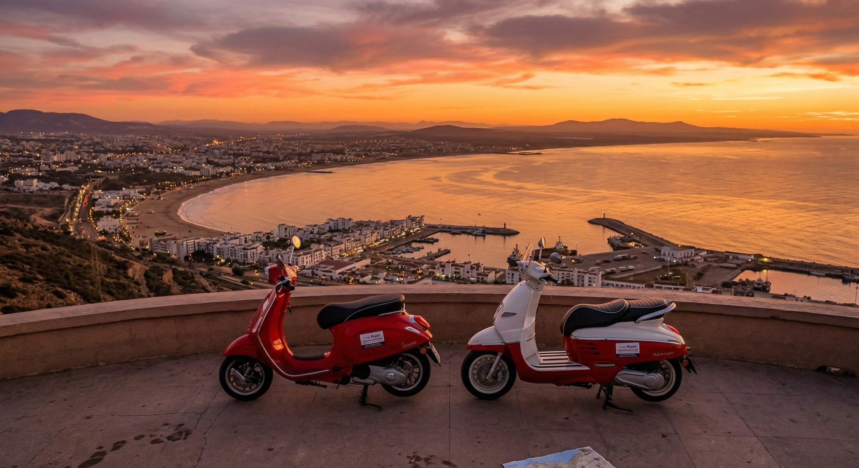 Two rental scooters parked at a sunset viewpoint overlooking the Agadir coastline in Morocco